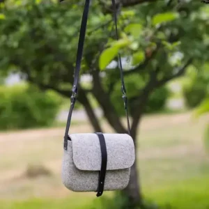 Grey Lahtiset shoulder bag with black vegetable-tanned leather straps hanging in natural light