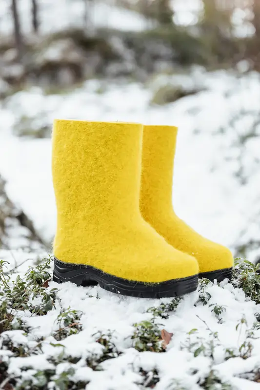 Keltaiset Lahtiset Nasta! -nilkkurit ulkona talvisessa maisemassa, nastoitettu pohja tuo pitoa.